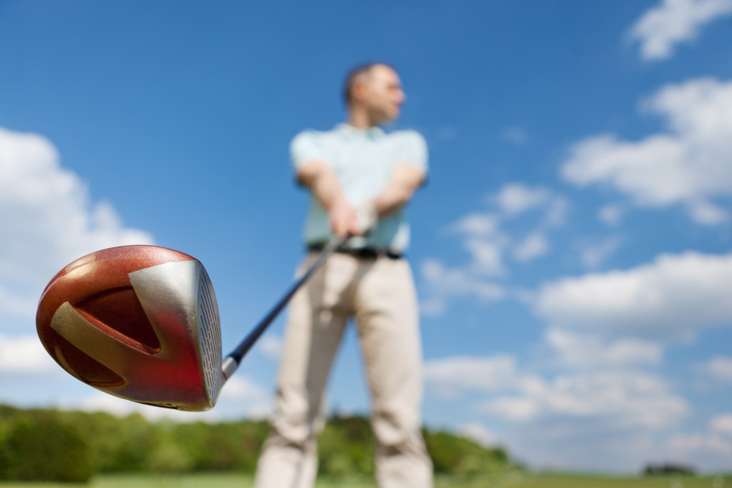 Low angle view of man holding golf club against sky