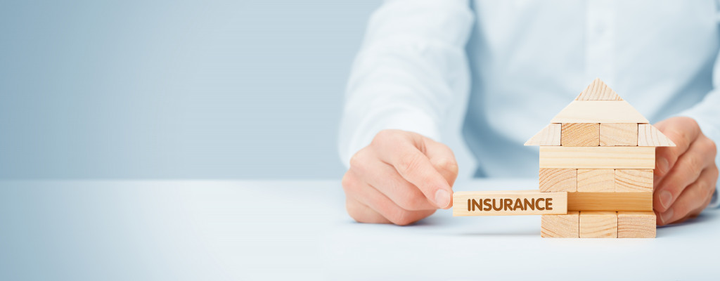 Person removing a block from a stack with the word insurance on it.
